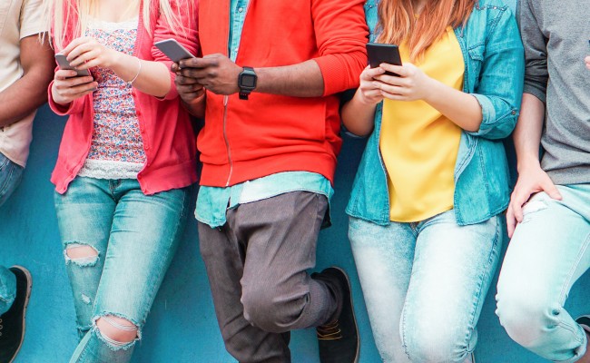 A group of young people are browsing on their mobile phones.